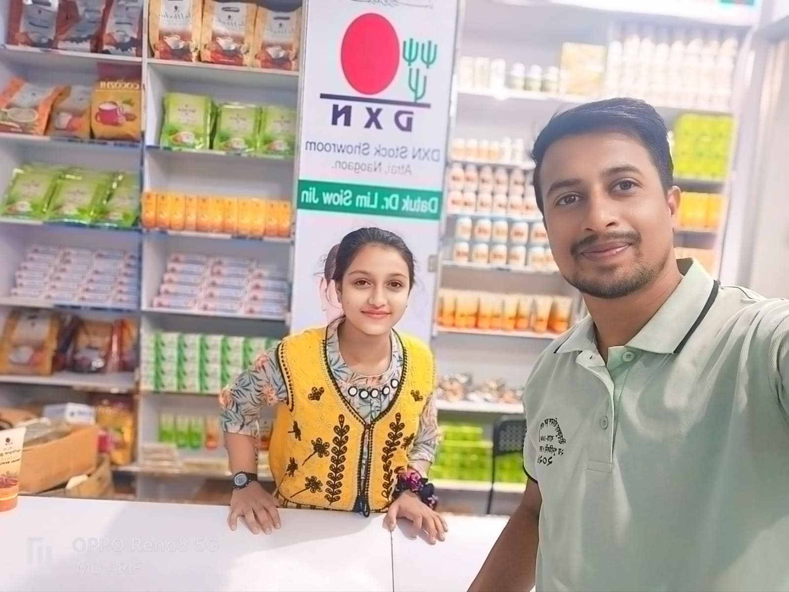 Two people standing in a store with shelves stocked with various packaged goods and health products.